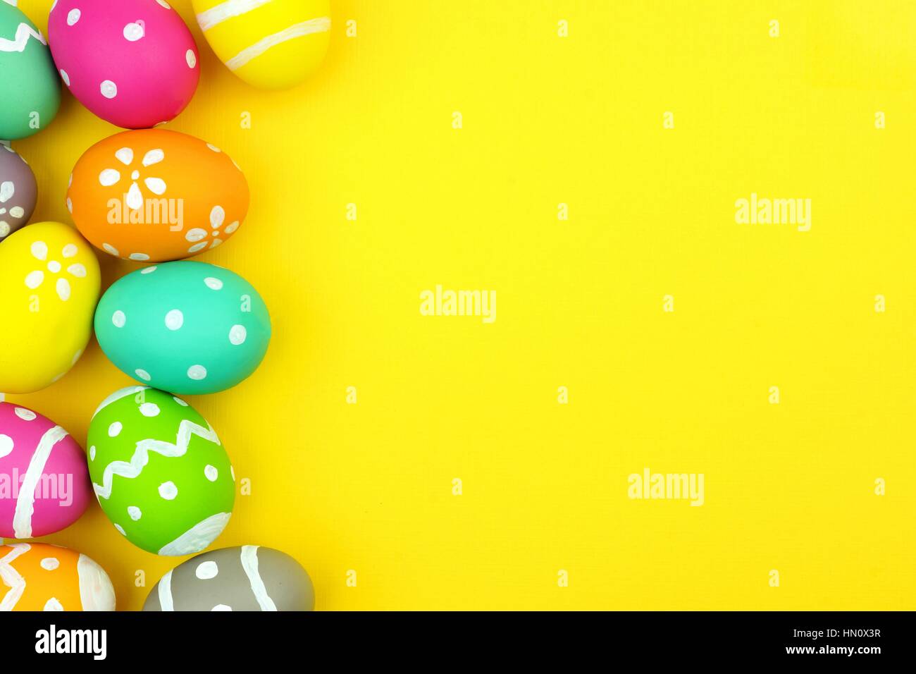 Colorful Easter egg side border over a yellow paper background Stock Photo