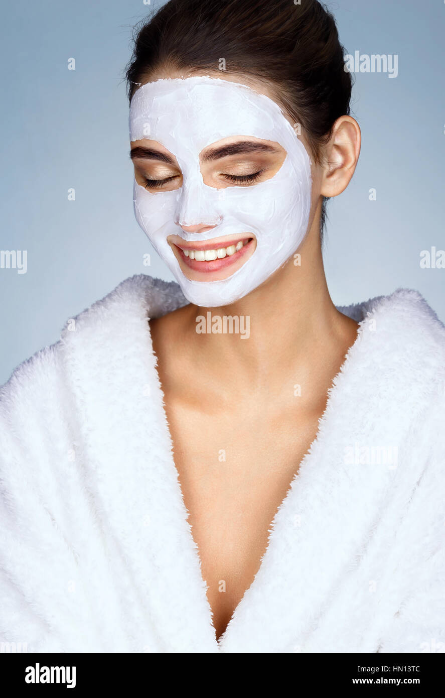 Laughing girl with moisturizing facial mask. Happy young woman smiling while wearing a face mask. Beauty & Skin care concept Stock Photo