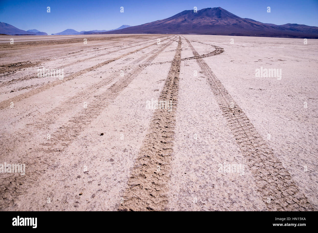 Car tracks on salt lake at Salar de Uyuni, Bolivia with Andean mountains in the background Stock Photo