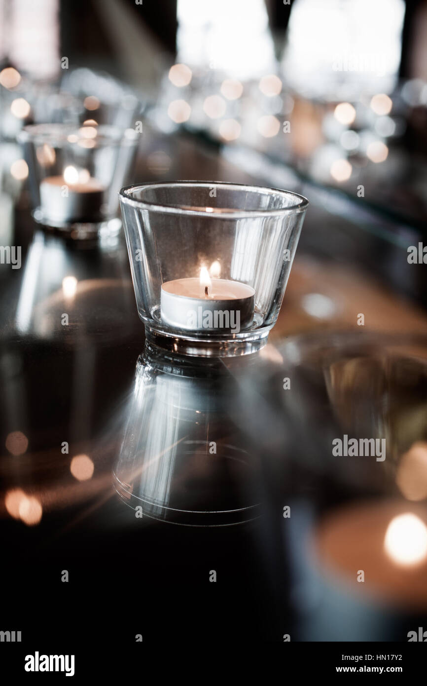 Tealights reflecting from glass table Stock Photo