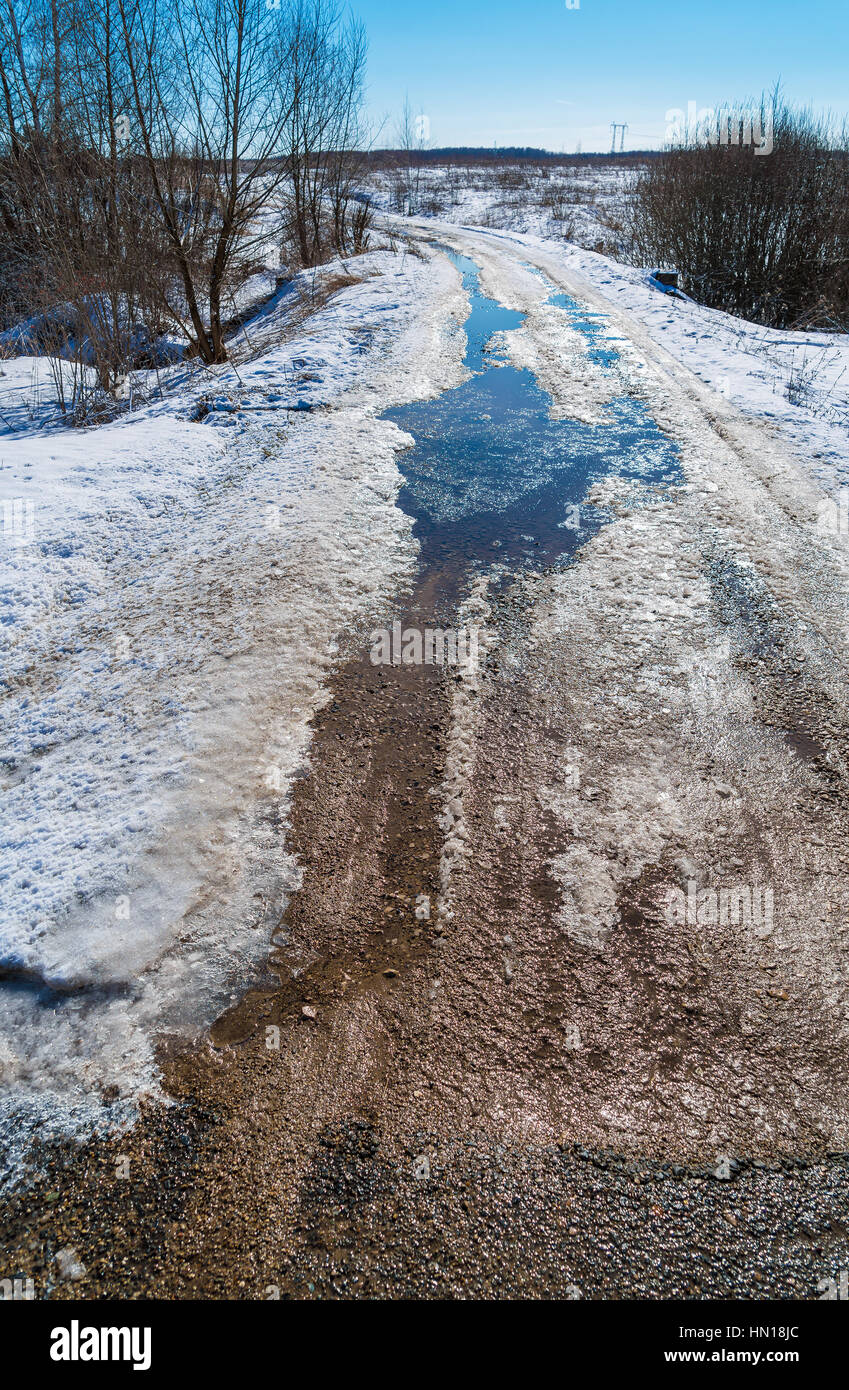 The road during the spring thaw with mud and puddles Stock Photo