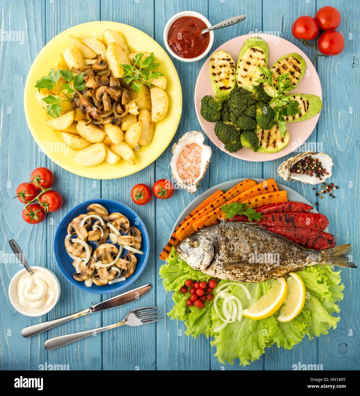 Delicious and nutritious meal rich in vitamins and minerals with fish and grilled vegetables: potatoes, mushrooms, carrot, tomato, broccoli, pepper, s Stock Photo