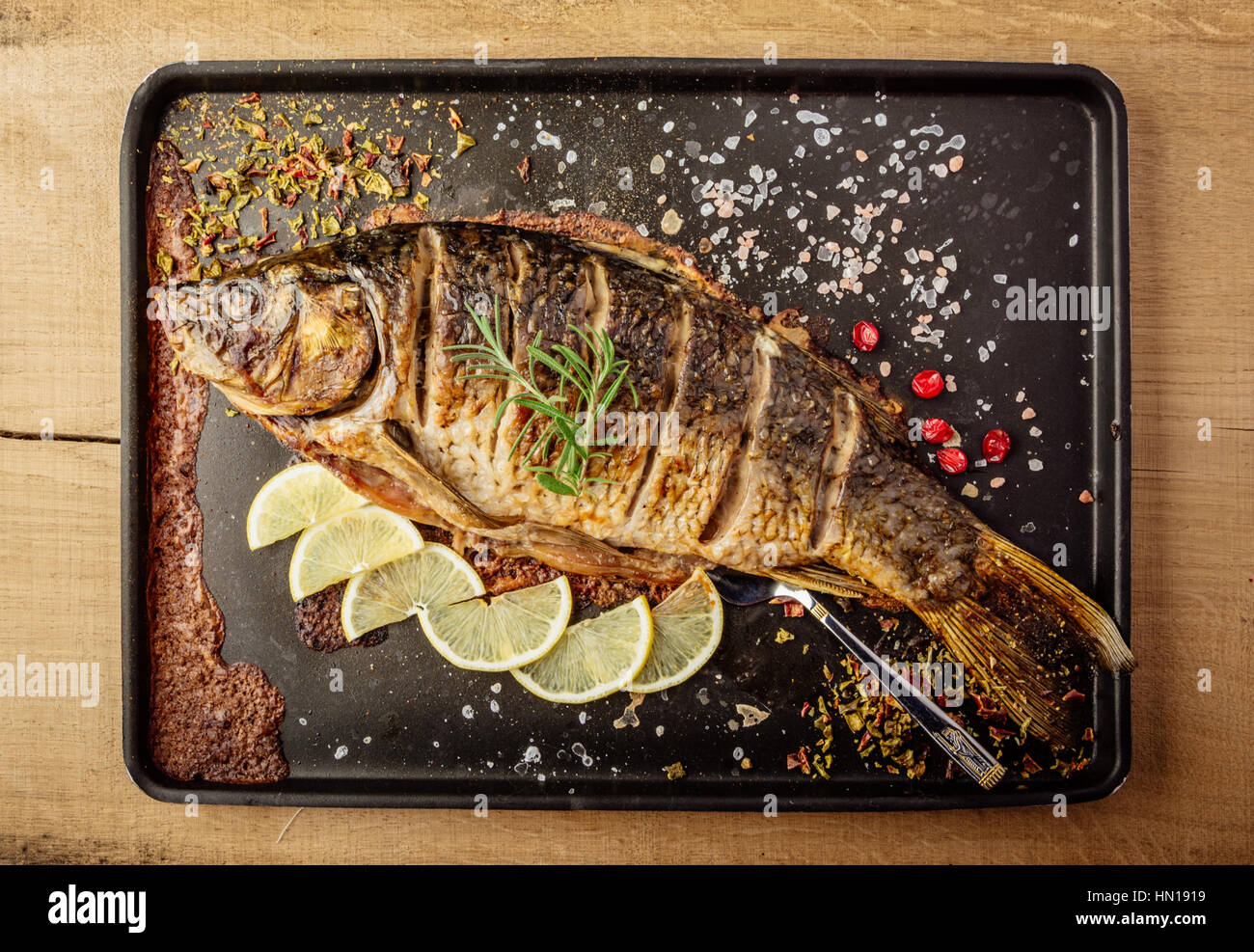 baked carp with spices and lemon on black pan Stock Photo