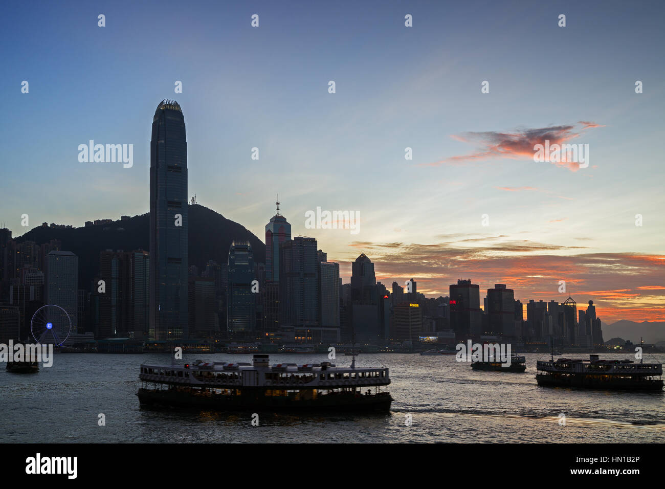 Silhouette of four Star Ferries, skyscrapers and other buildings on Hong Kong Island in Hong Kong, China, at sunset. Viewed from the Tsim Sha Tsui. Stock Photo