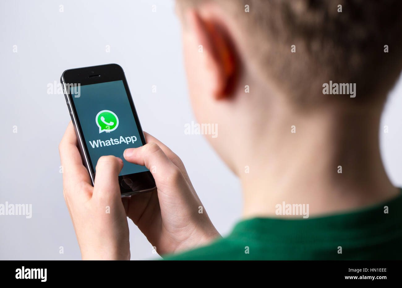 A teenage boy using WhatsApp on a mobile phone Stock Photo