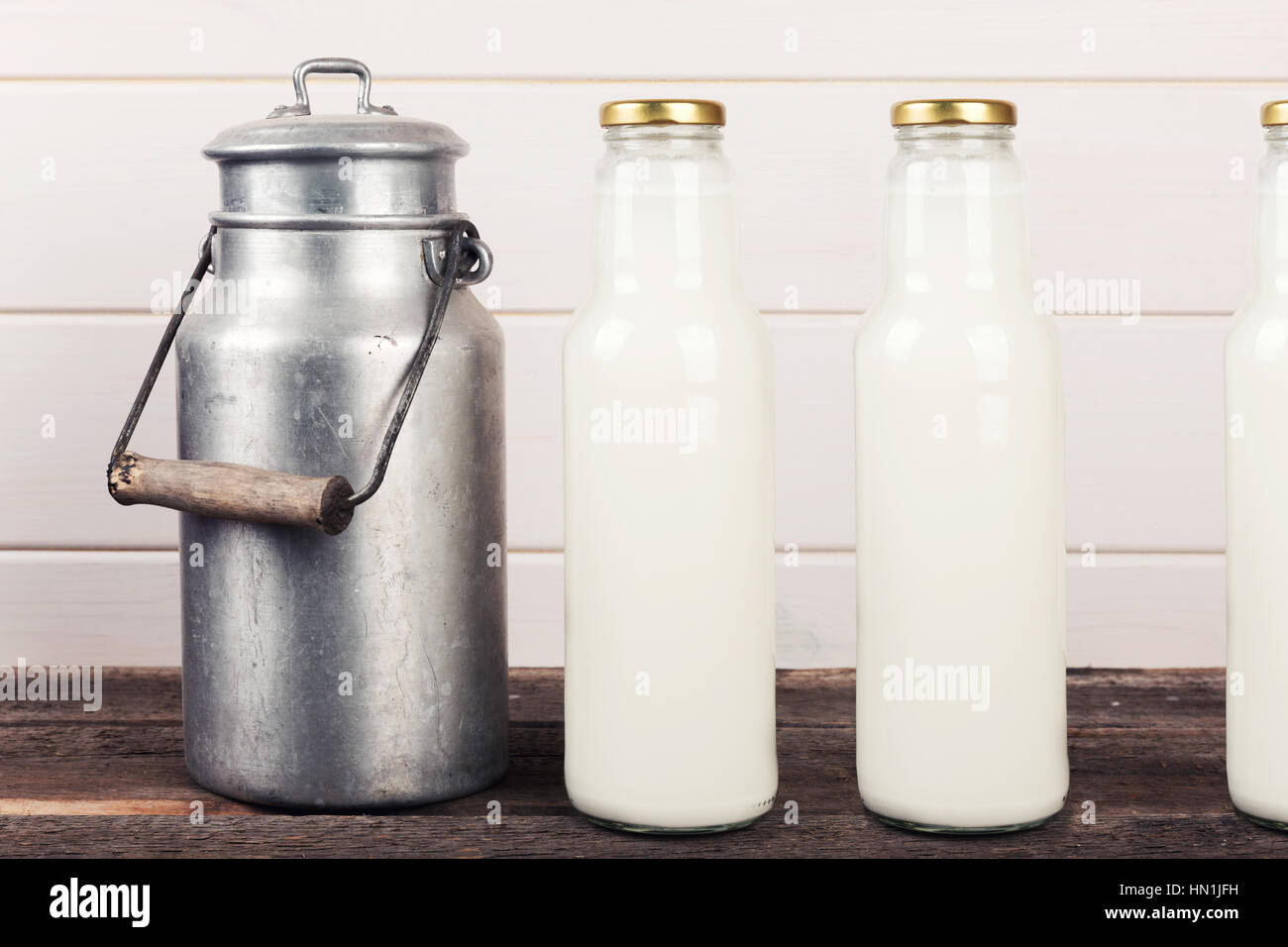 old milk can and bottles on wooden table Stock Photo