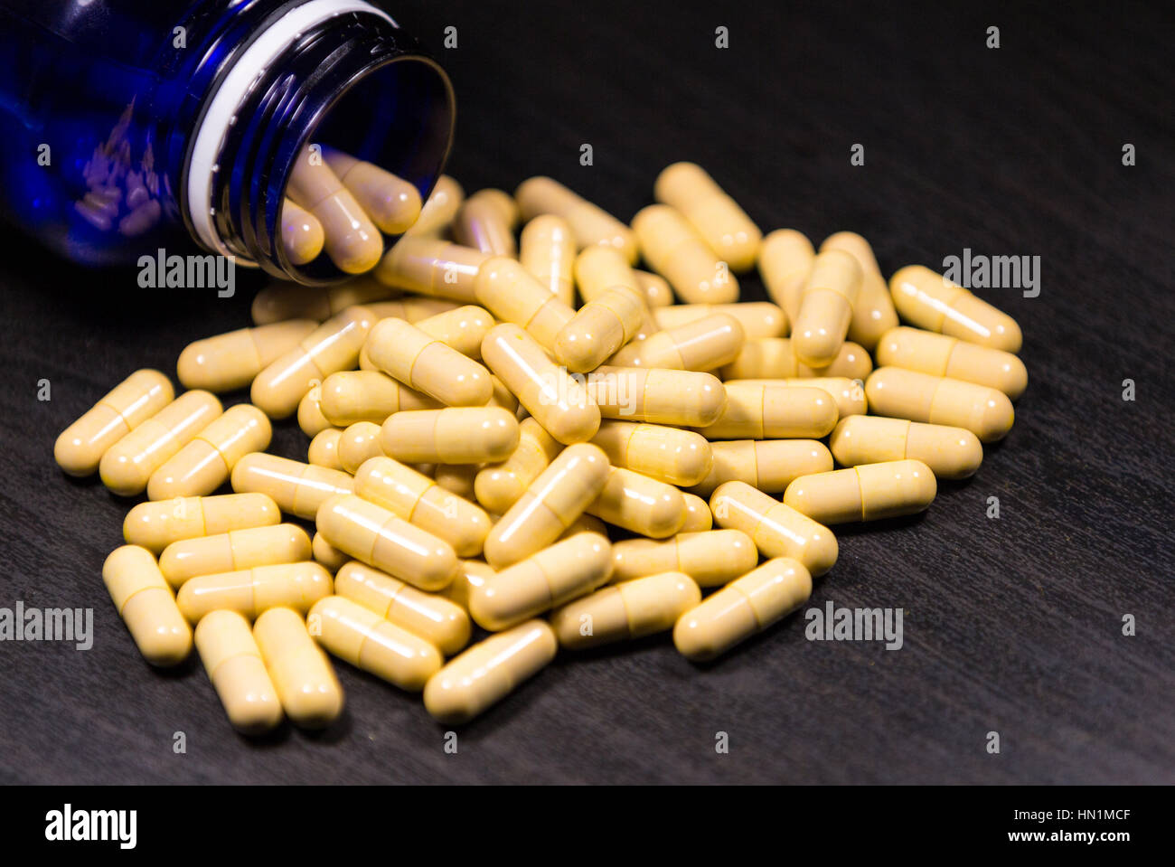 Pill bottle spilling pills on to surface isolated on a black background Stock Photo