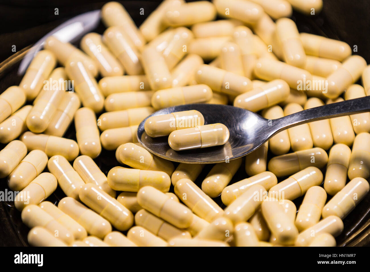 Spoonful of medicine capsules on a plate. Signifying drug addiction, healthy eating and lifestyle, dieting and slimming Stock Photo