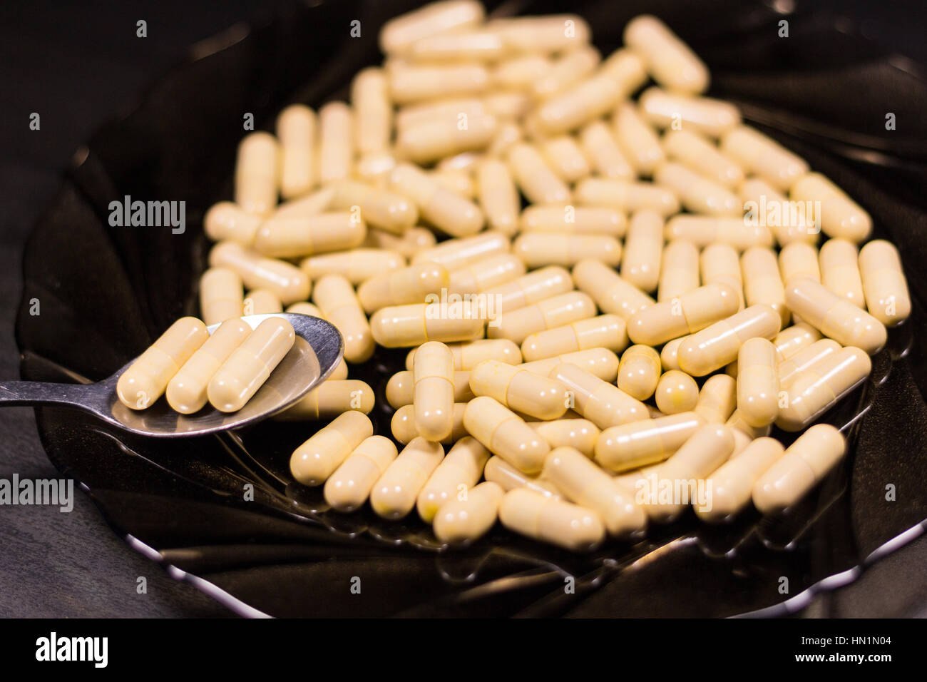Spoonful of medicine capsules on a plate. Signifying drug addiction, healthy eating and lifestyle, dieting and slimming Stock Photo