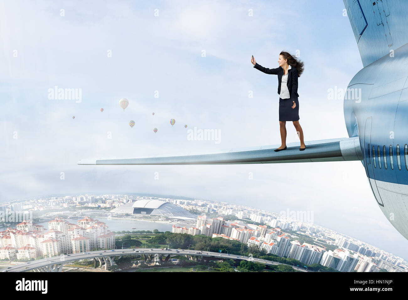 Businesswoman standing on airplane wing and taking selfie Stock Photo