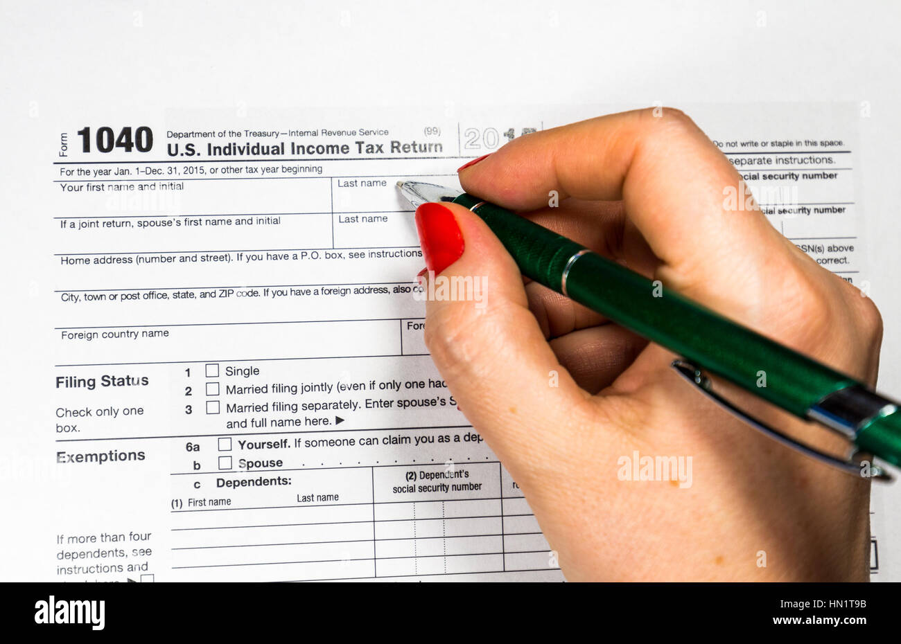 Business woman fills the tax form 1040 with pen and calculator Stock Photo