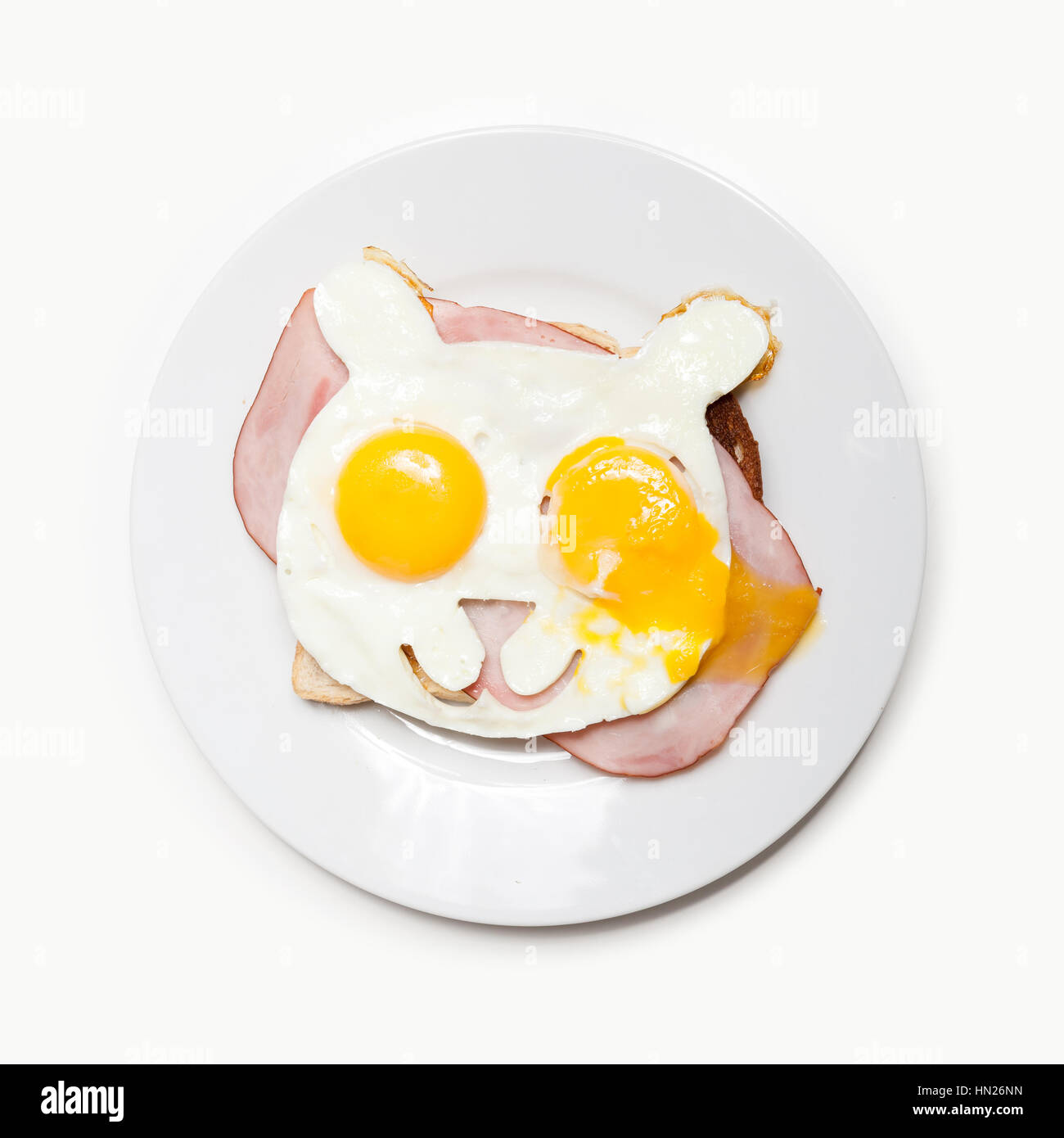 Fried eggs in the shape of a bear on toast with ham. Stock Photo