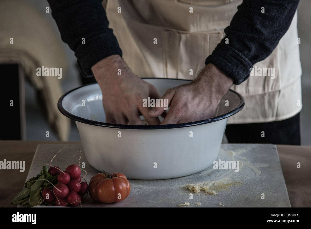 hands of a person kneading dough in a bowl on marble carving board on