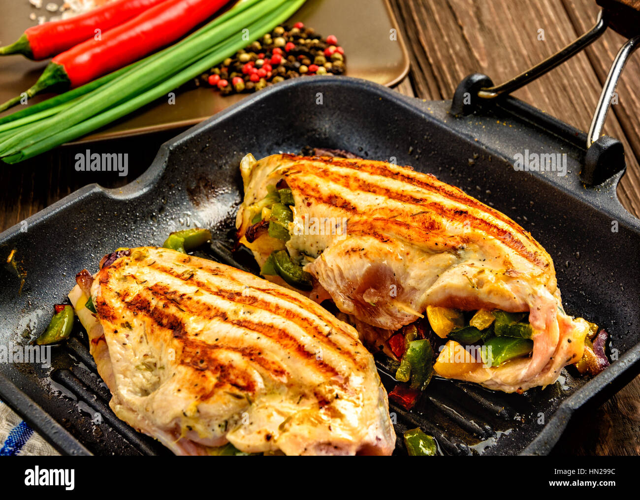 Juicy chicken fillet on a frying pan grill on a brown wooden background. Close up Stock Photo