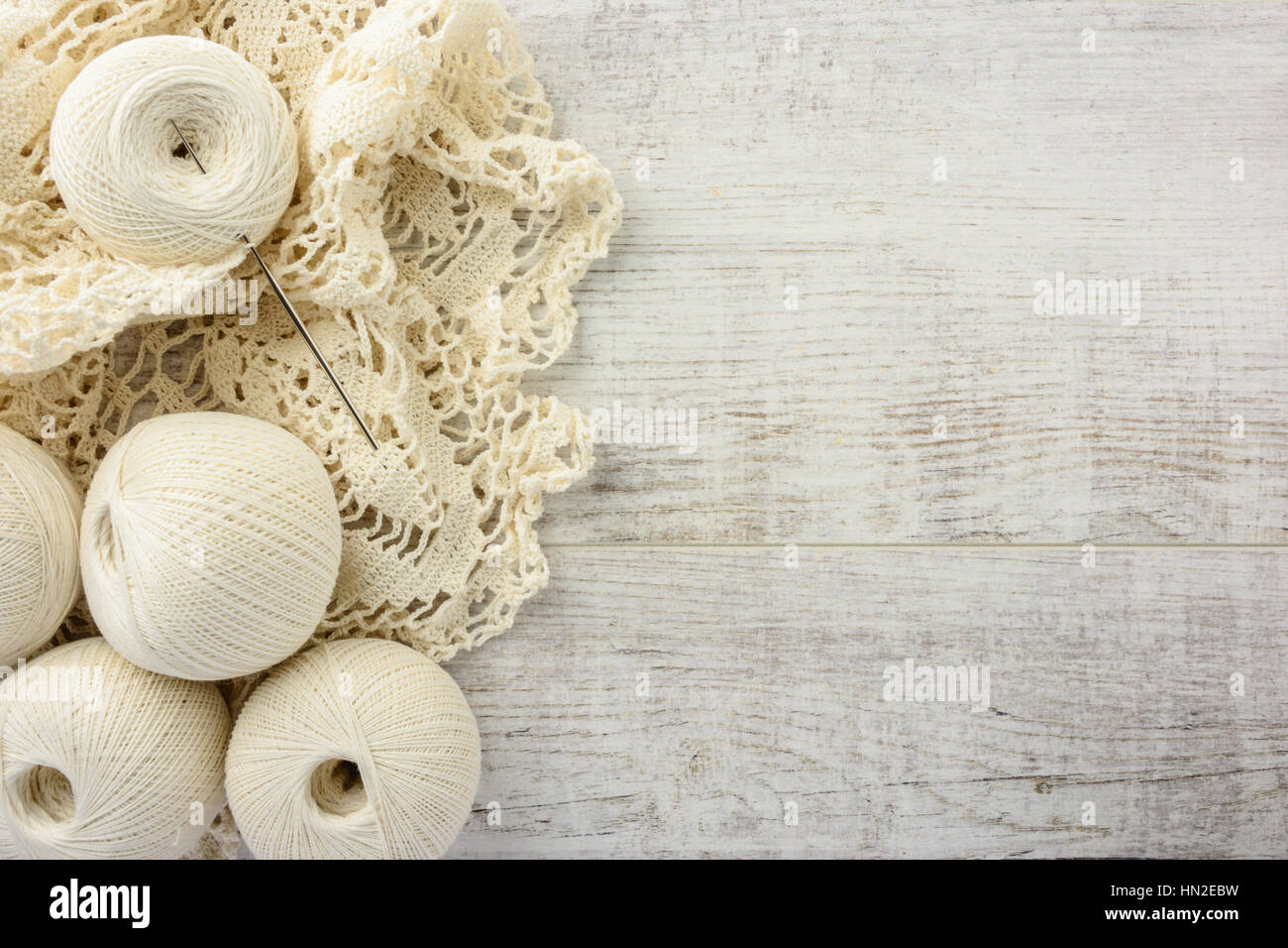 crochet tablecloth, crochet hooks and balls of cotton thread on a white wooden table. top view, copy space Stock Photo