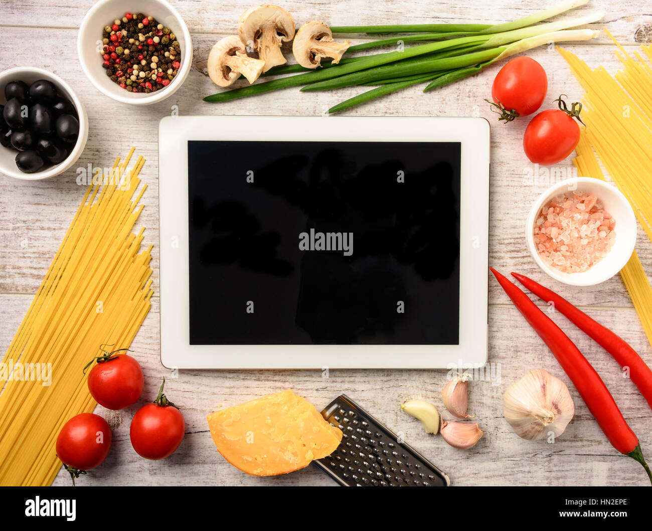 Ingredients for cooking healthy Italian food and tablet on a white wooden table with space for an object in a home kitchen. top view. Stock Photo