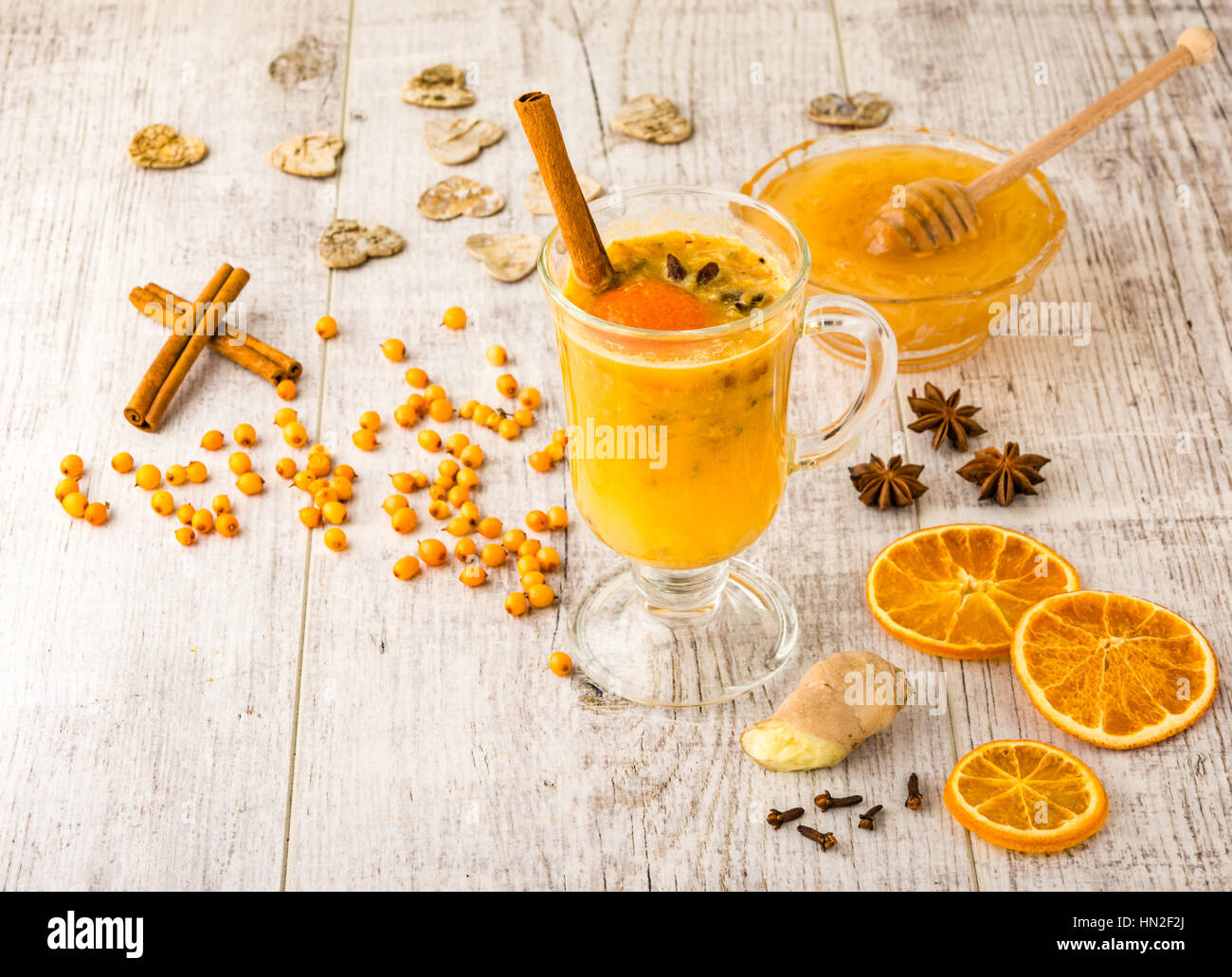sea buckthorn tea with honey, sea buckthorn , cinnamon, carnation and orange slices on a white wooden table Stock Photo