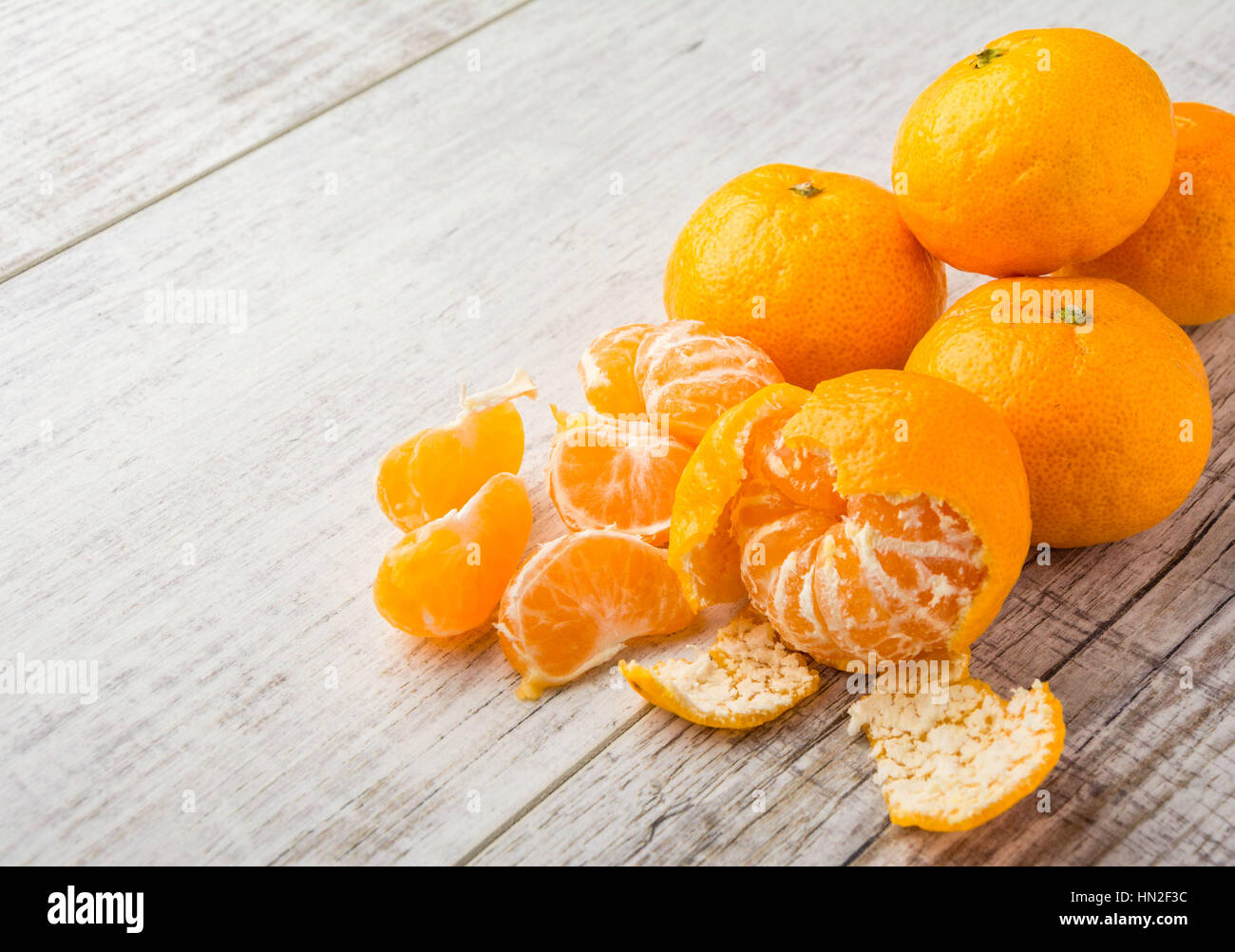 mandarines, peeled tangerine and tangerine slices on a white wooden table Stock Photo