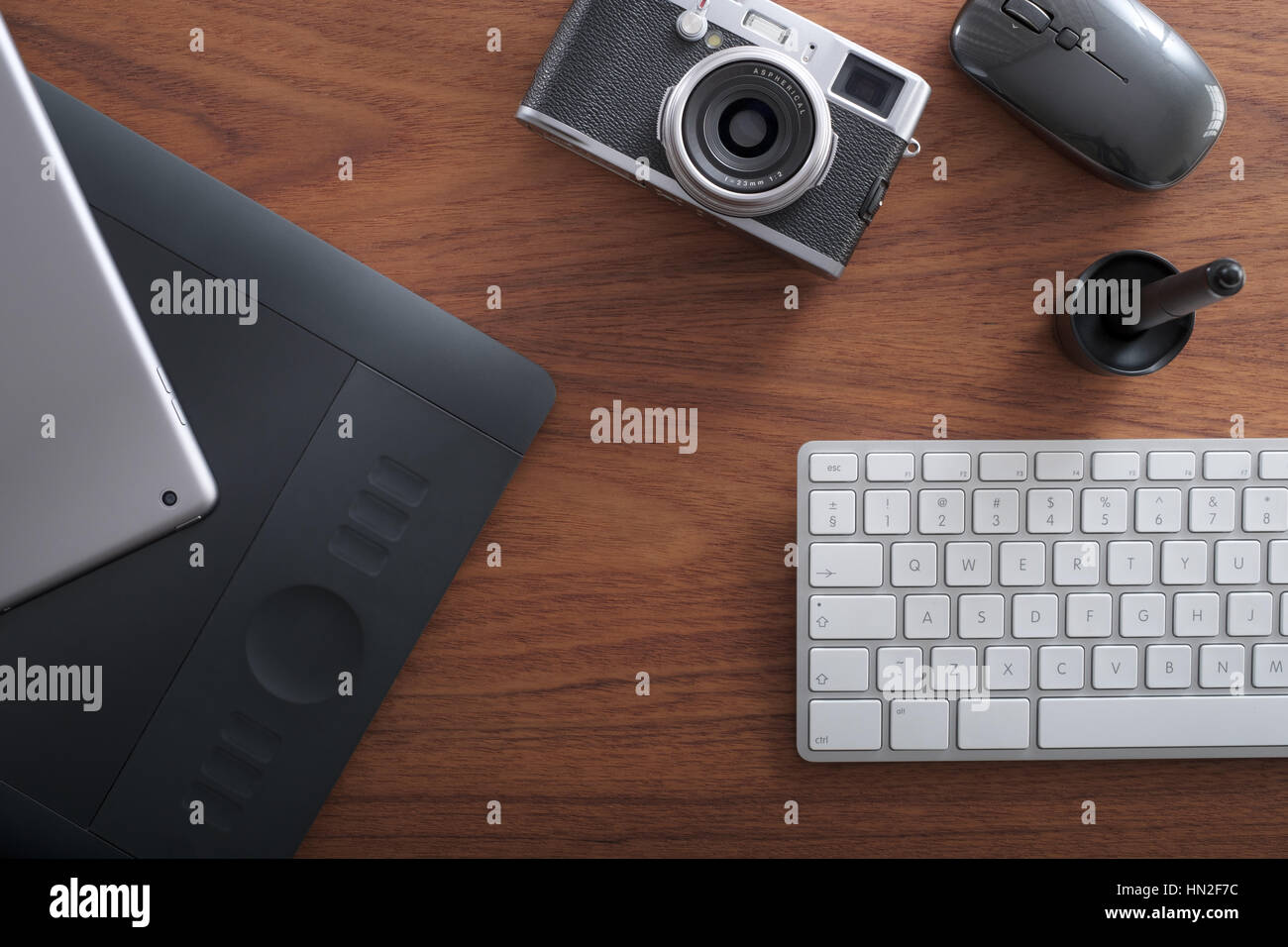 Office desk with camera, digital pad, graphic tablet, wireless mouse and keyboard Stock Photo