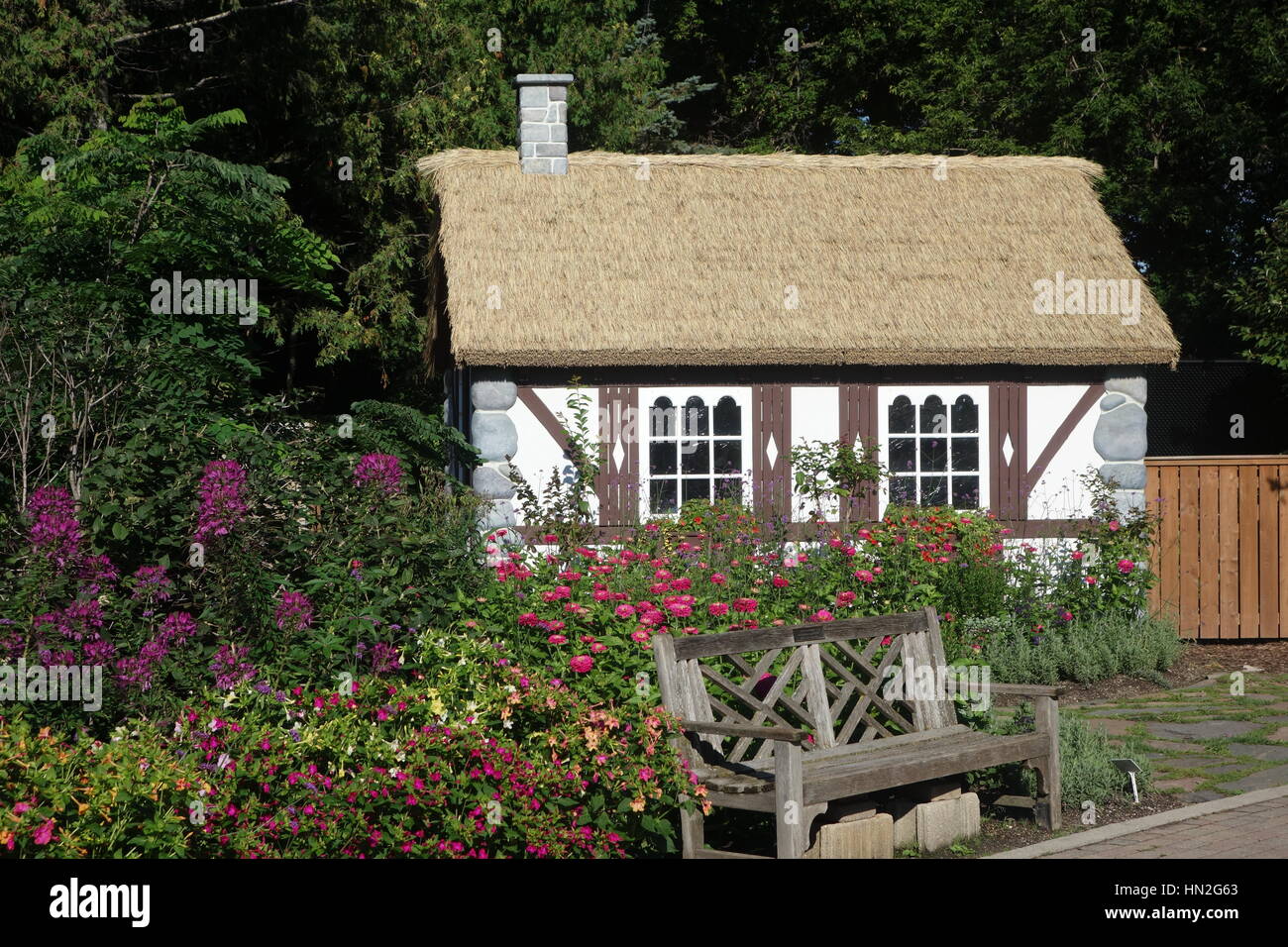 Tudor style English cottage with thatch roof in garden setting. Stock Photo
