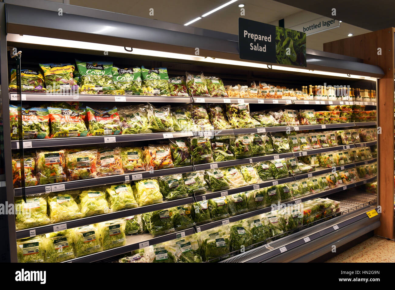 Pre-packed bags of salad on a refrigerated shelf in a supermarket Stock Photo