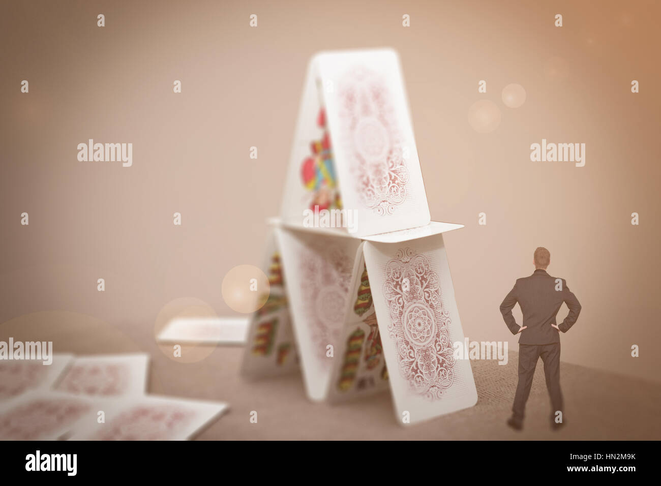tiny businessman standing near house of cards Stock Photo