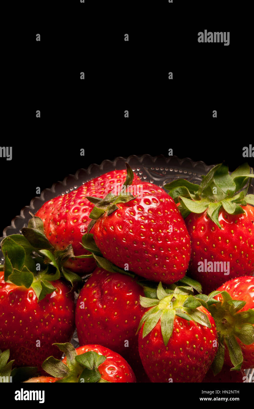 strawberries on a glass stand against black background Stock Photo - Alamy