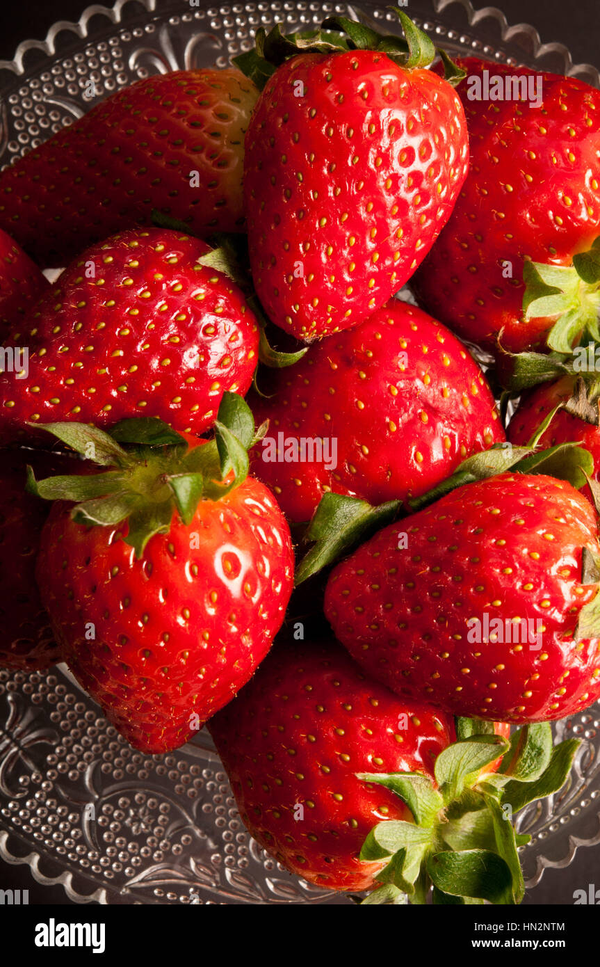 strawberries on a glass stand against black background Stock Photo - Alamy