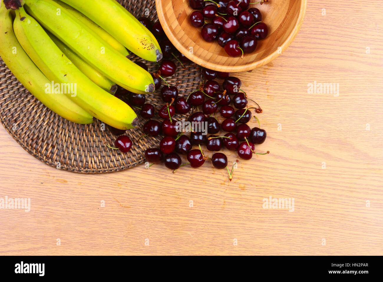 A Wooden Bowl of Mixed Fruits on a Wooden Background, Banana, Cherries, Peaches Stock Photo