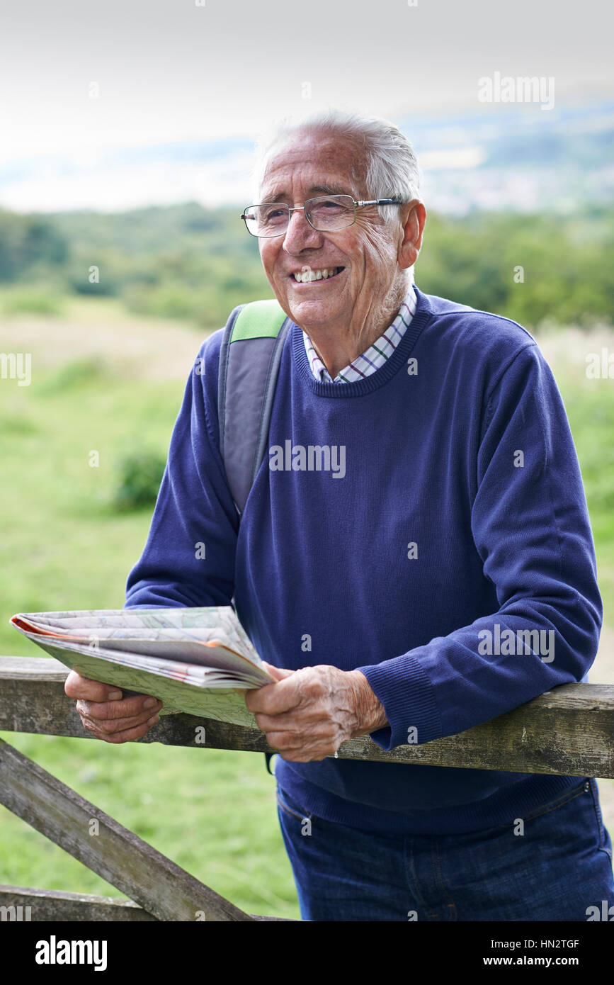 Senior Man Hiking In Countryside Looking At Map Stock Photo