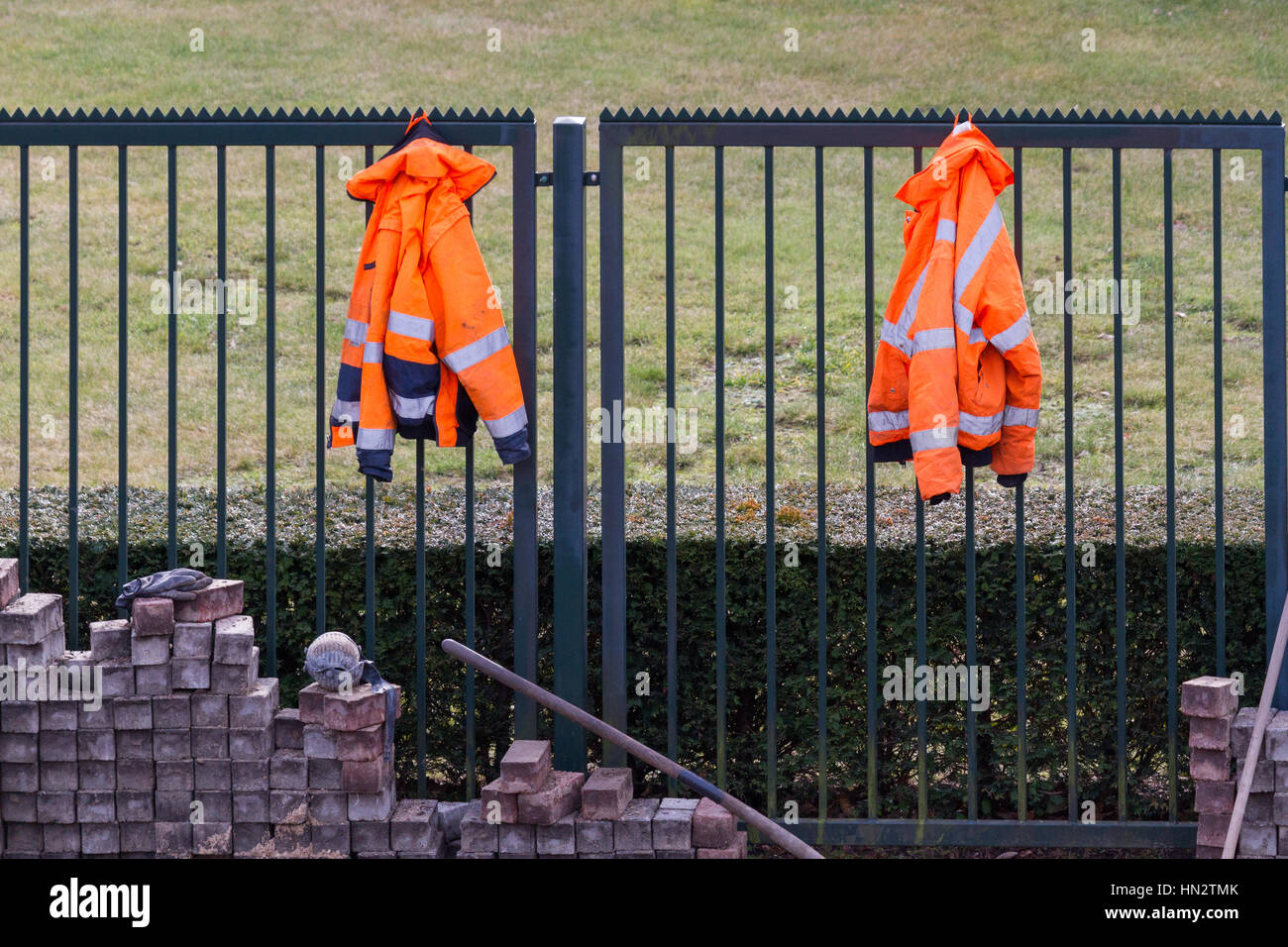 Two fluorescent jackets hanging above bricks at a building site Stock Photo