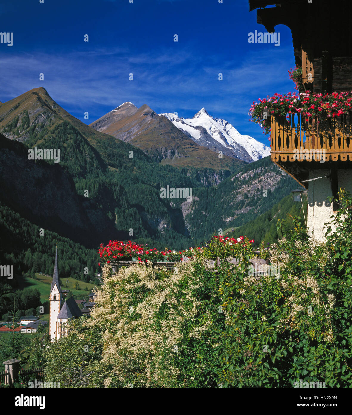 Tirolean house with balcony in Heiligenblut, snow capped Grossglockner mountain in distance, Carinthia, Austria. Stock Photo