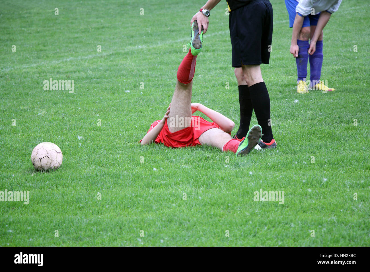 Referee provides assistance injured player at the football match Stock Photo