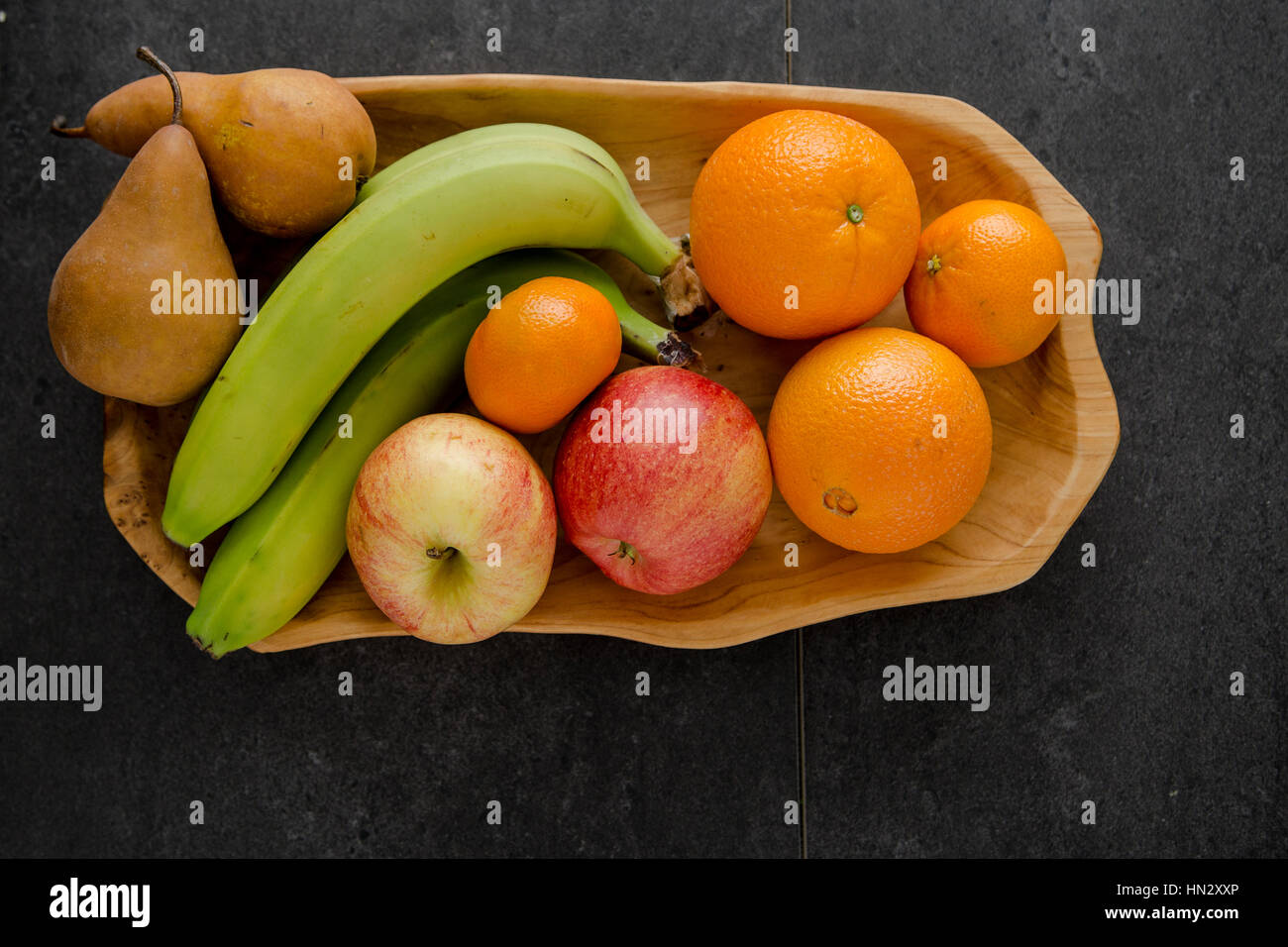 A hand carved wooden bowl with organic fruit Stock Photo