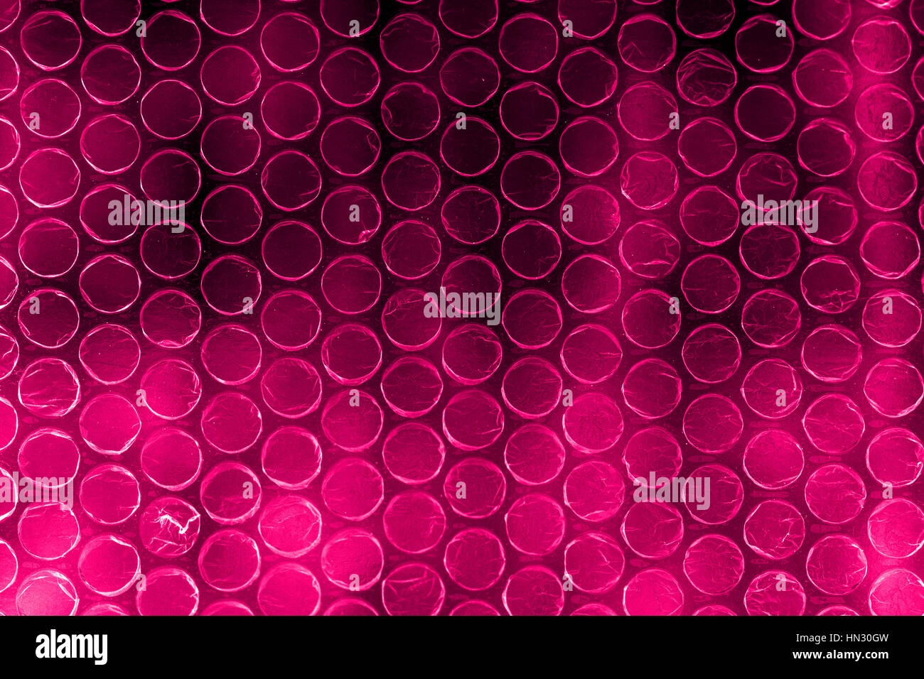 Plastic polymer bubble wrap in high contrast vivid reddish pink color Stock Photo