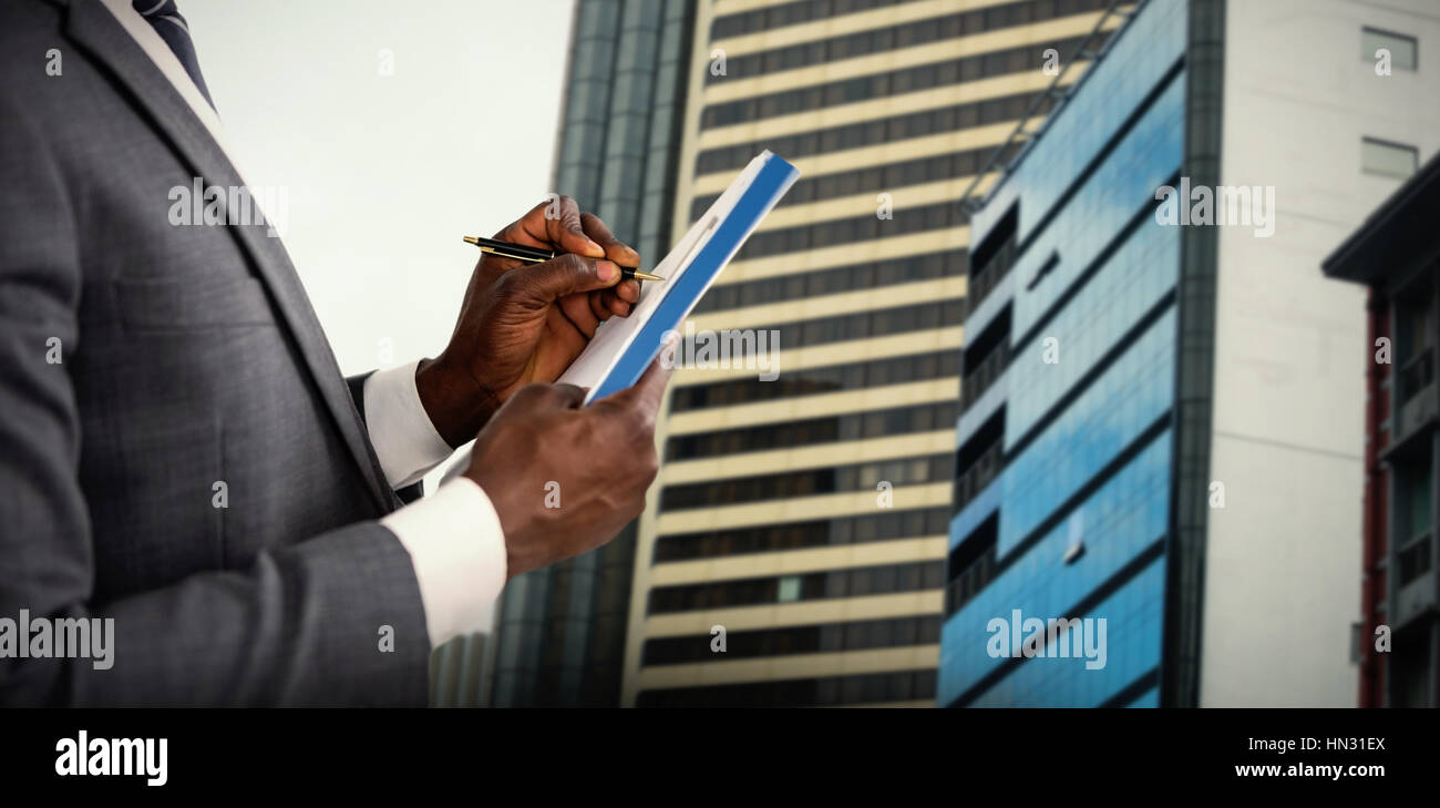 Hands of man signing document against view of modern glass office ...