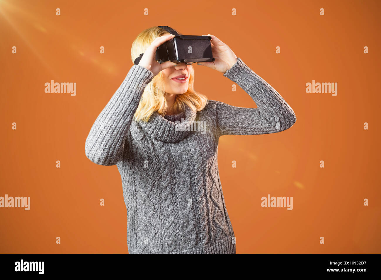 Woman With Blond Hair Using Virtual Reality Headset Against Orange