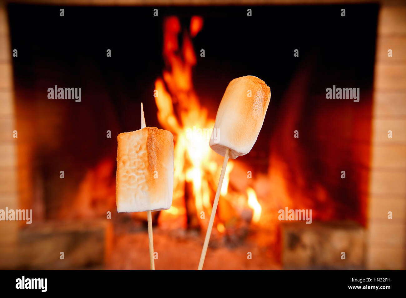 Two marshmallows on sticks being roasted by the fire Stock Photo