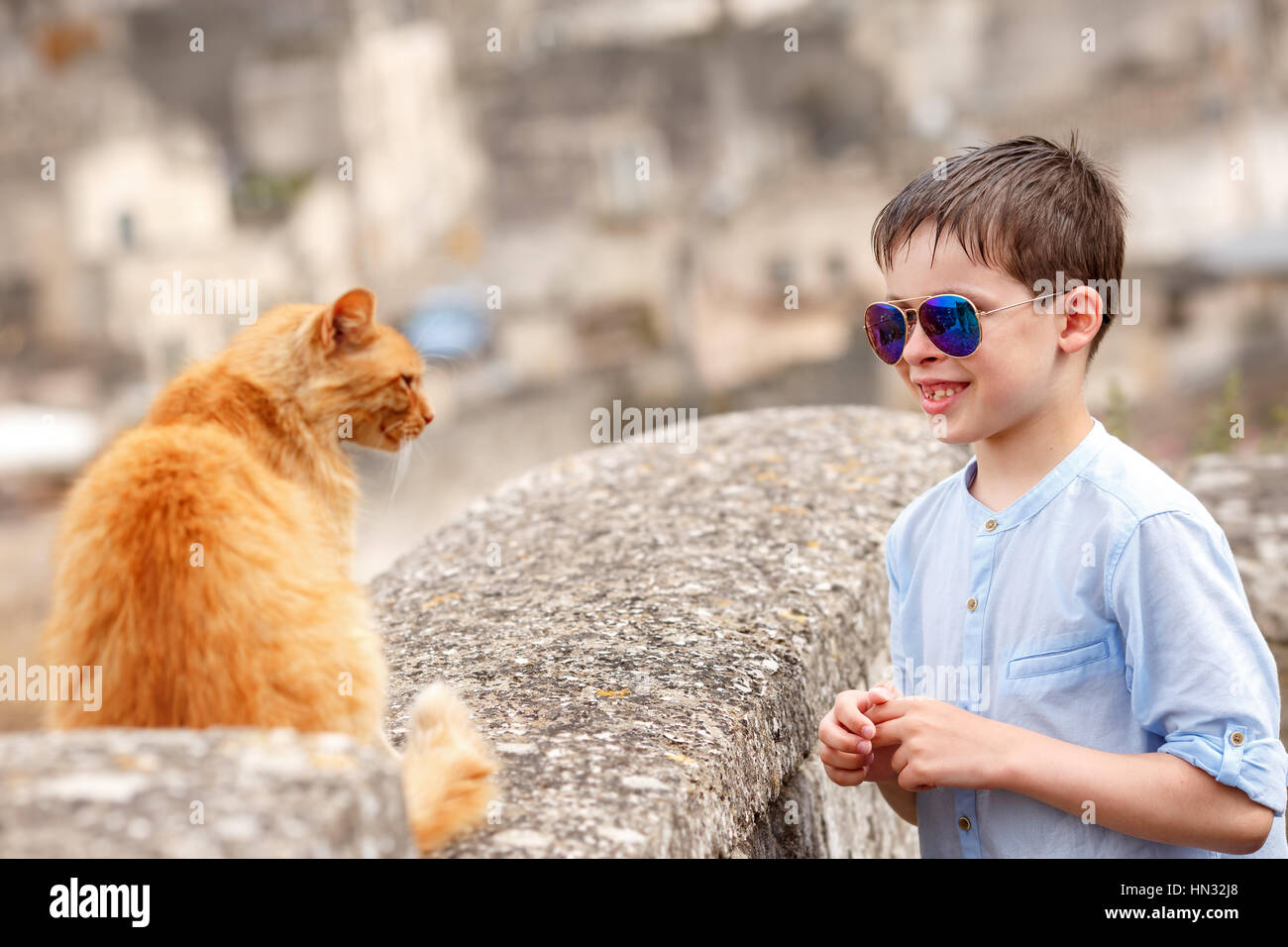 Cute little boy met a cat while walking at typical italian town Stock Photo