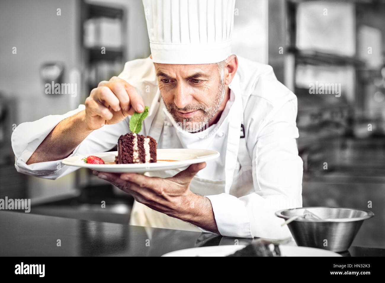 Closeup of a concentrated male pastry chef decorating dessert in the kitchen Stock Photo