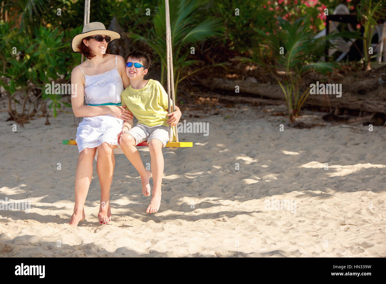 Young beautiful woman swinging her son on a tropical beach, Koh Samui island. Thailand, Asia Stock Photo