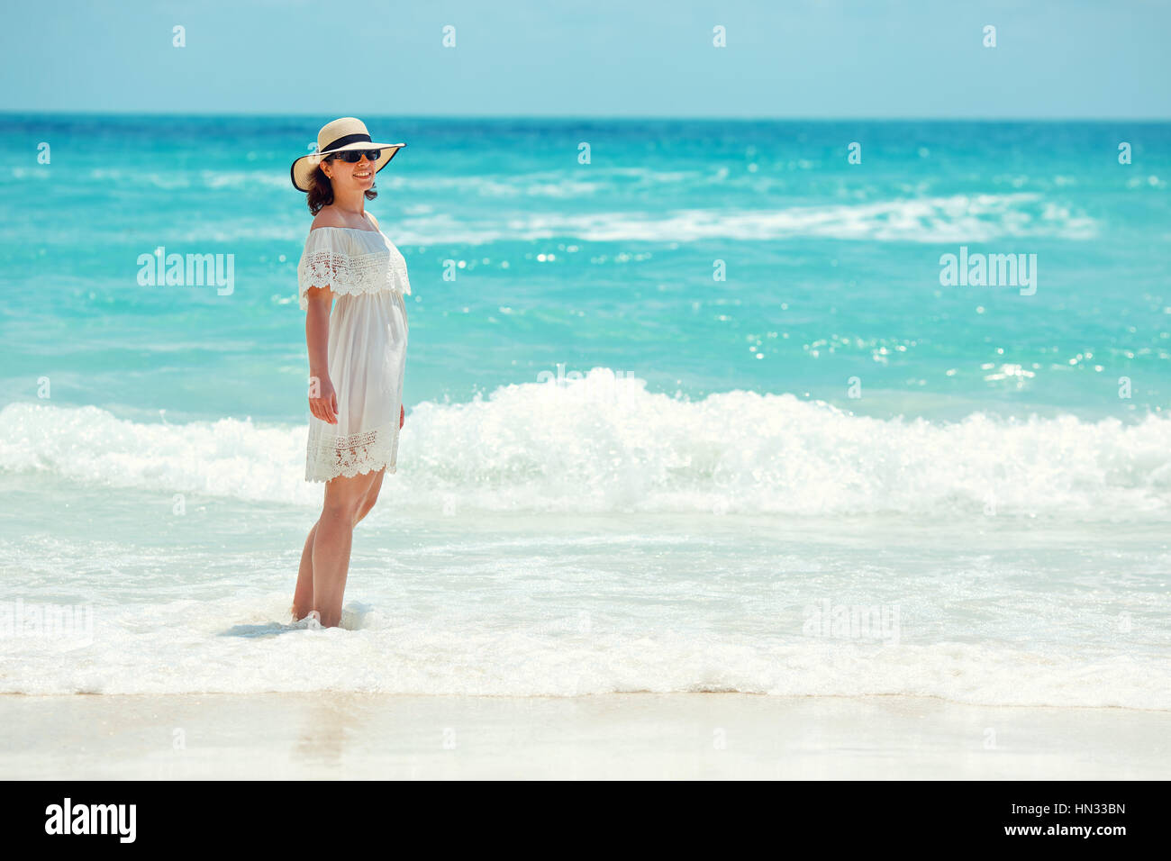 Woman in white dress walking on the beach during summer vacation Stock Photo