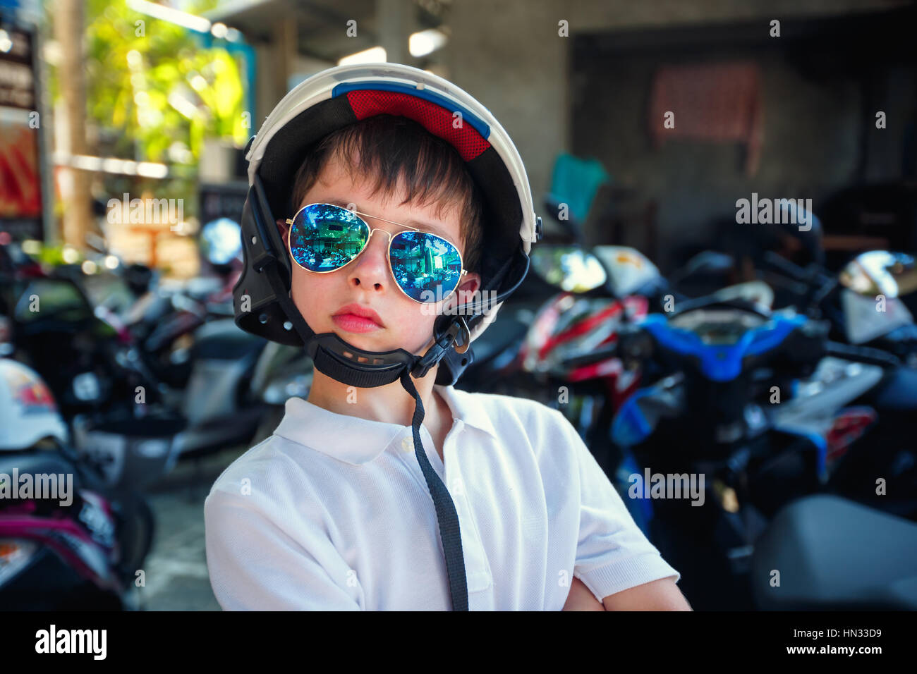 Portrait of cute little boy in helmet and sunglasses before riding a motorcycle Stock Photo