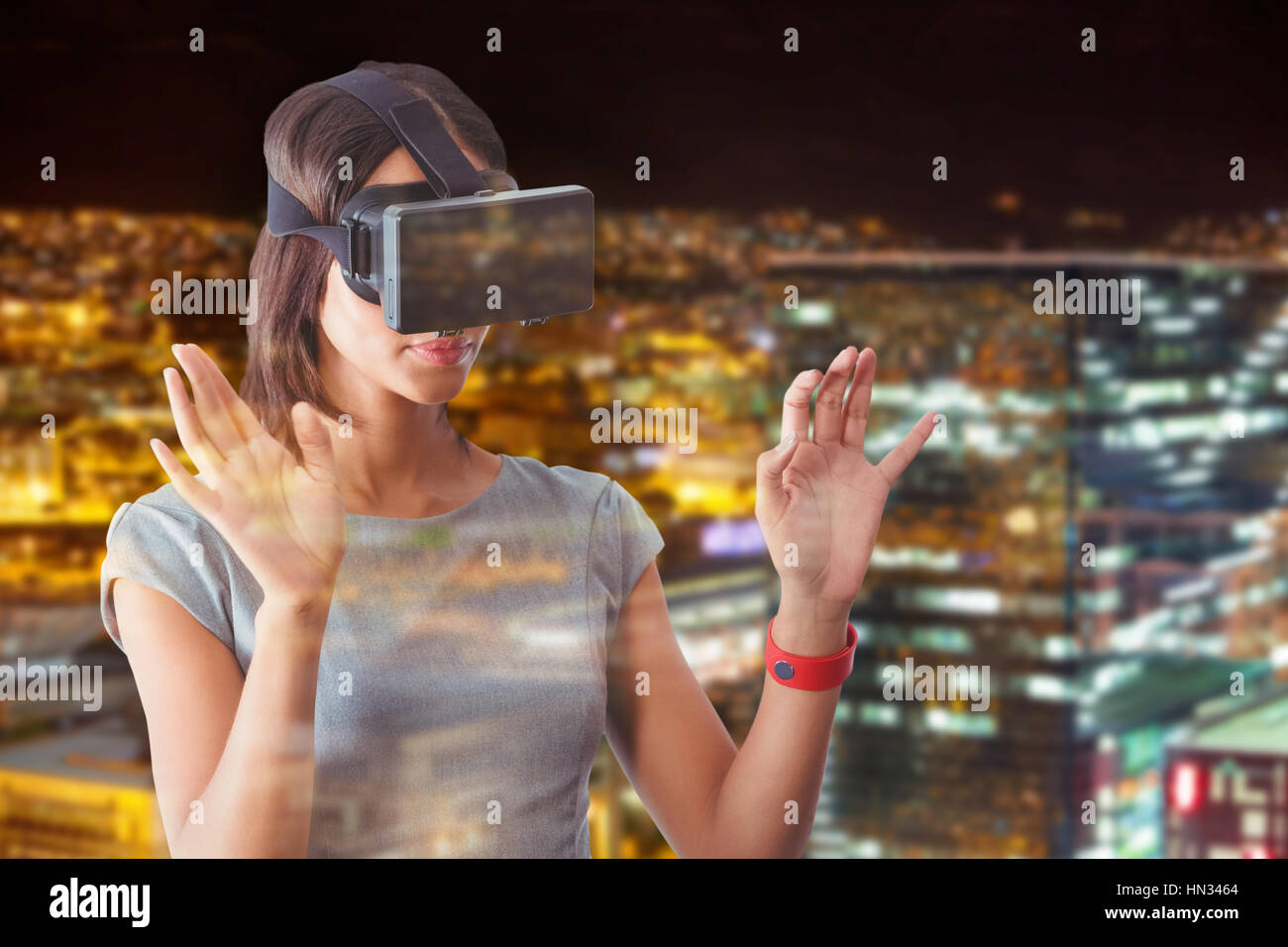 Businesswoman holding virtual glasses on a white background against high angle view of illuminated crowded cityscape Stock Photo