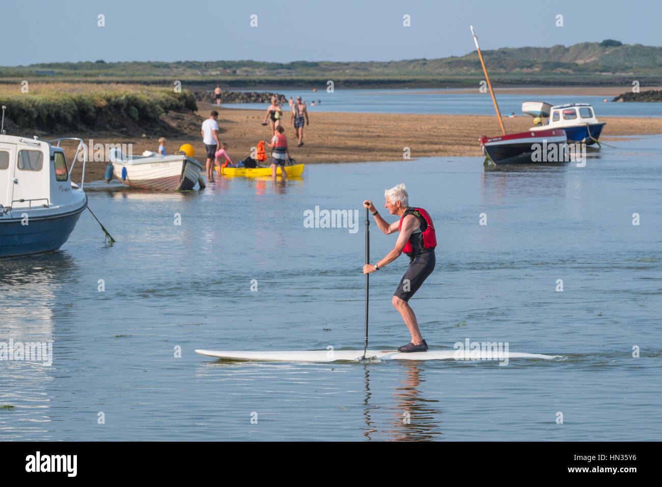 A paddle boarder with swimmers and boaters enjoying fine weather. Stock Photo