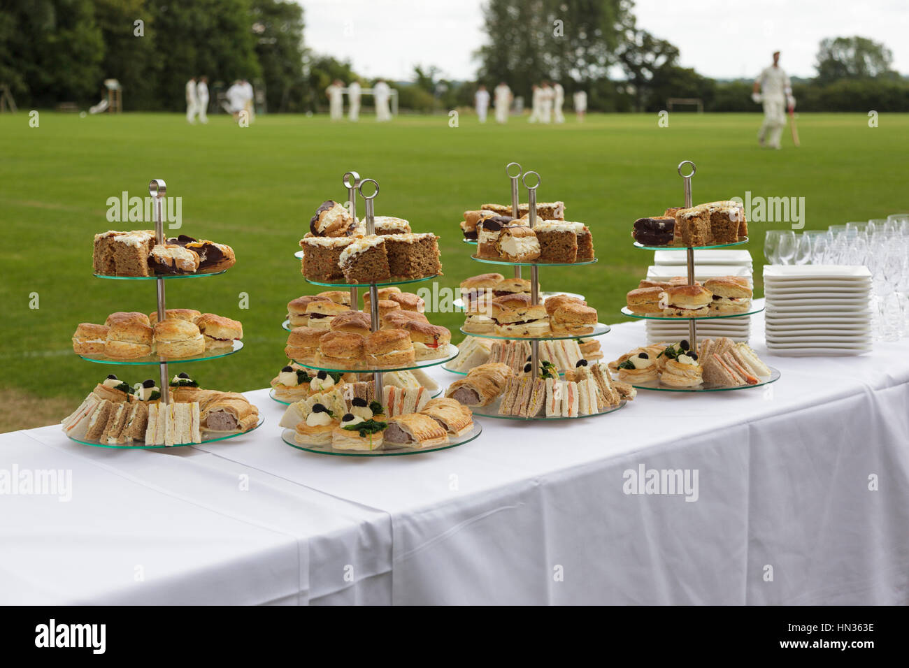 Afternoon tea laid out on tables next to a village cricket pitch. Stock Photo