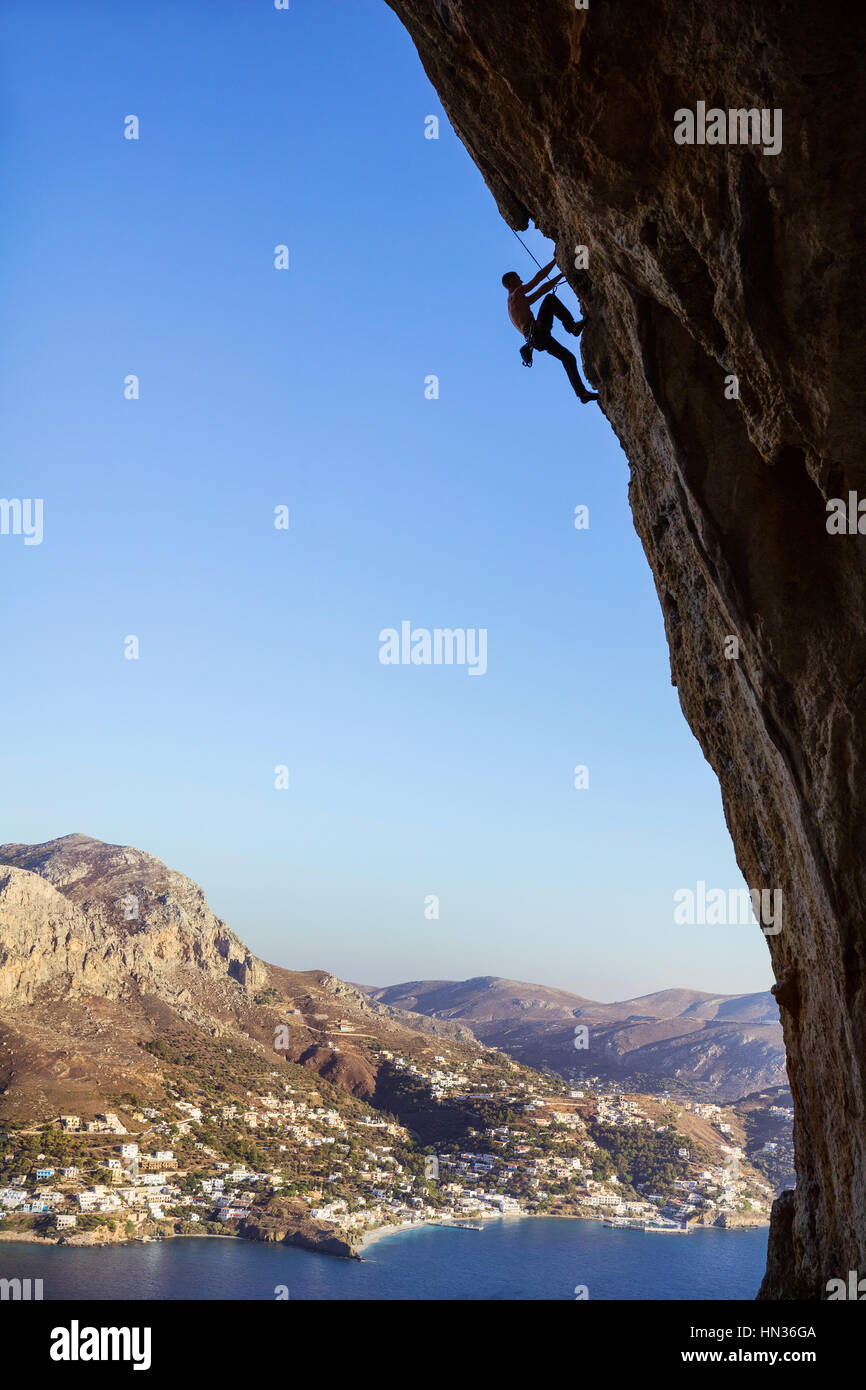 Young man climbing along rocks Stock Photo - Alamy