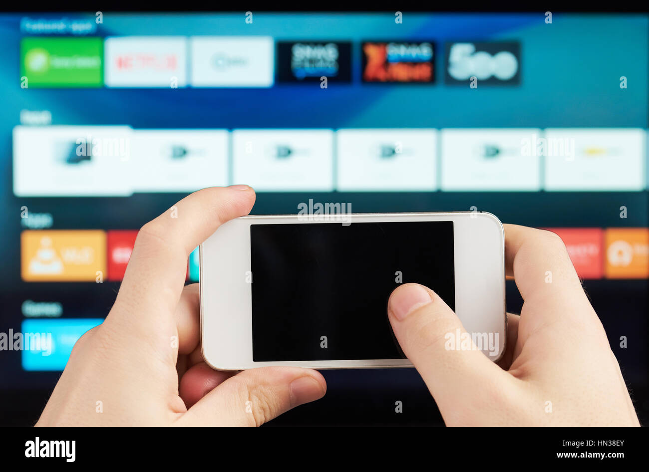 using smartphones as tv remote on blurred background Stock Photo
