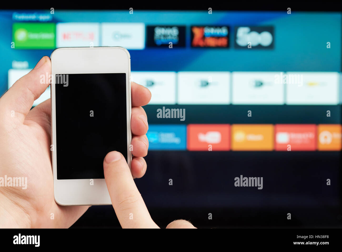 using smartphone as tv remote control on blurred background Stock Photo