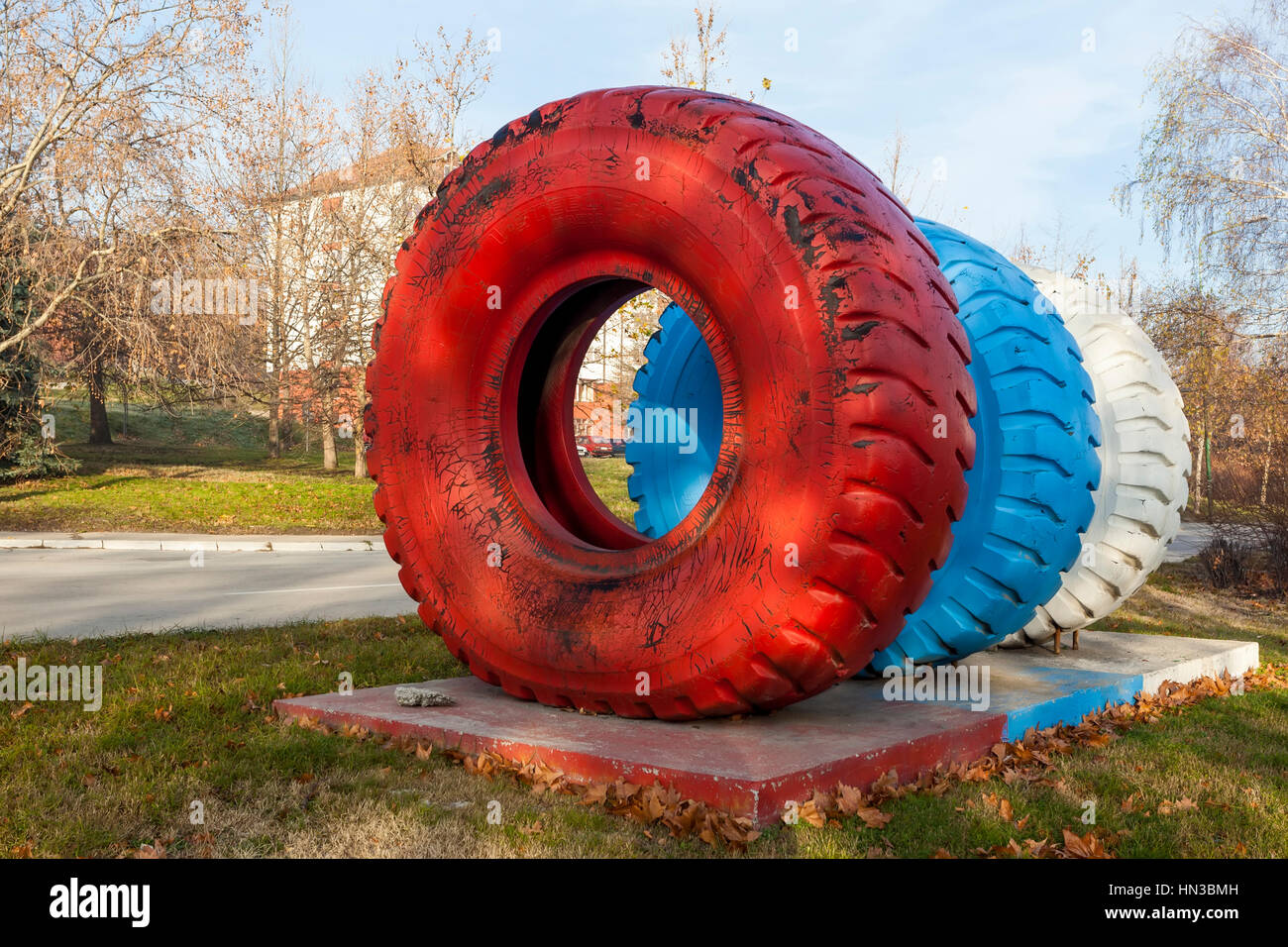 Dumper truck tires of different sizes placed as a monument in the industrial city Stock Photo